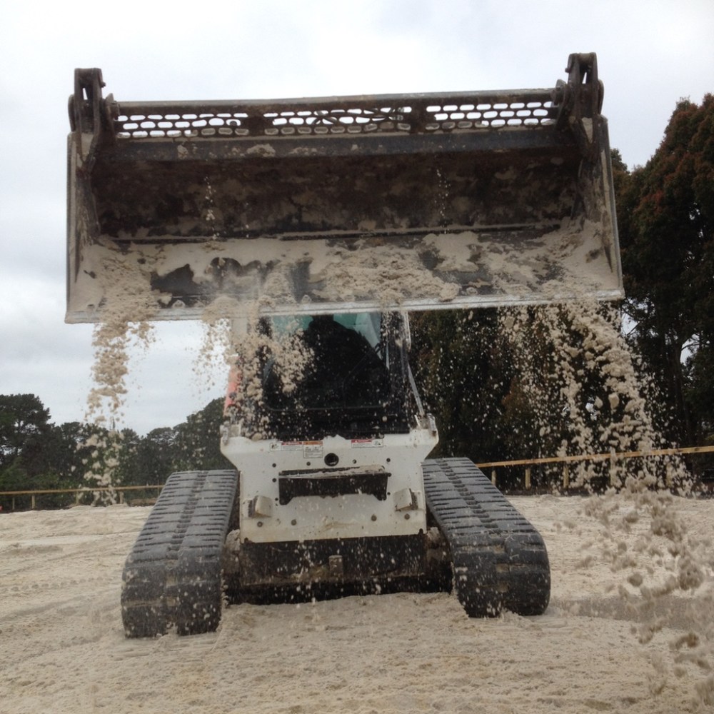 Spreading sand on dressage arena